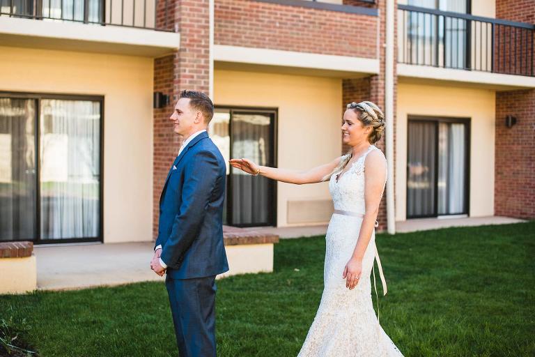 bride reaching out to groom during first look,